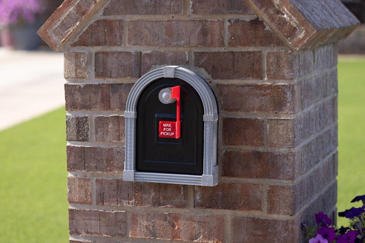 A brick mailbox with a U.S. Mail sign and a red flag indicating mail for pickup.