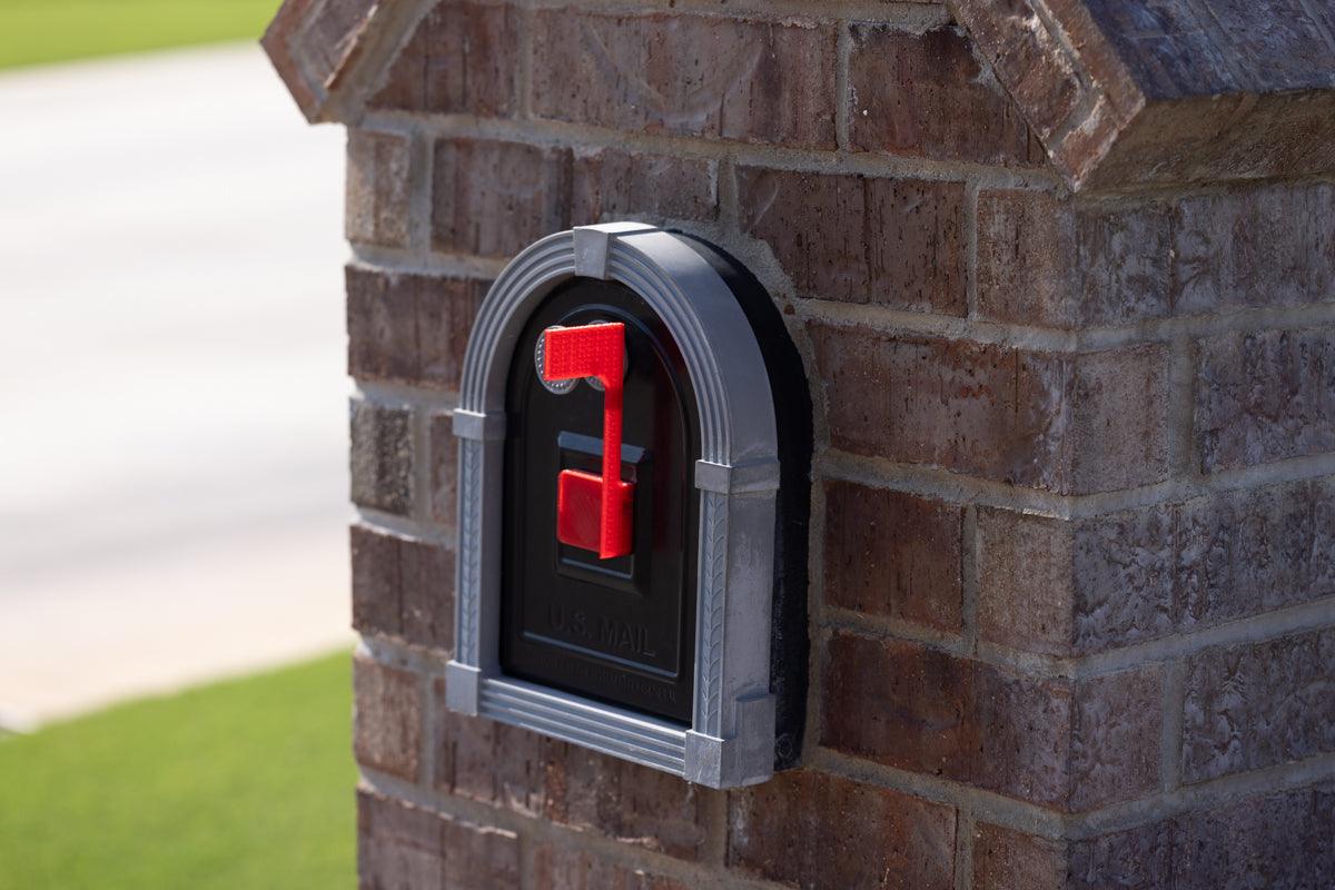 A brick mailbox with a black and red mailbox flag.