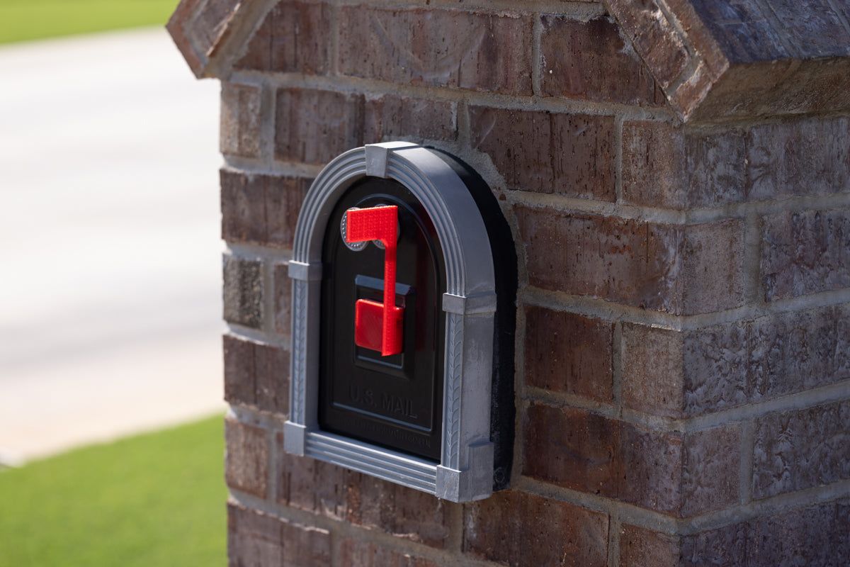 bricks surrounding a black mailbox with a red magneitc flag on the front