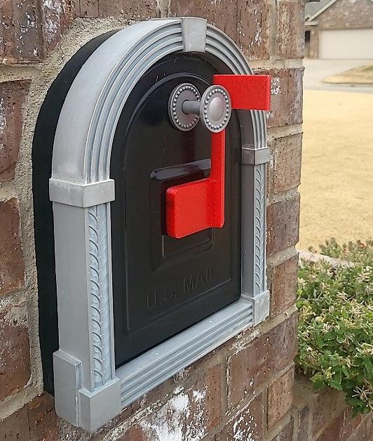 Black mailbox with a red flag mounted on a brick pillar.